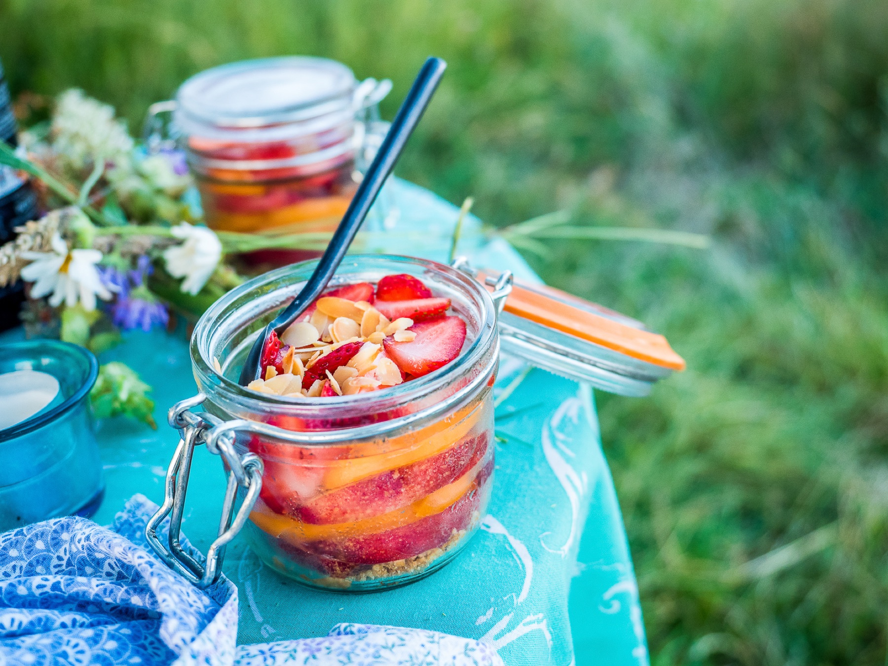 Bocaux de préparation culinaire disposés sur une table bleue en pleine nature